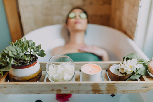 Woman relaxing in bath with lit candles for her health and wellness.